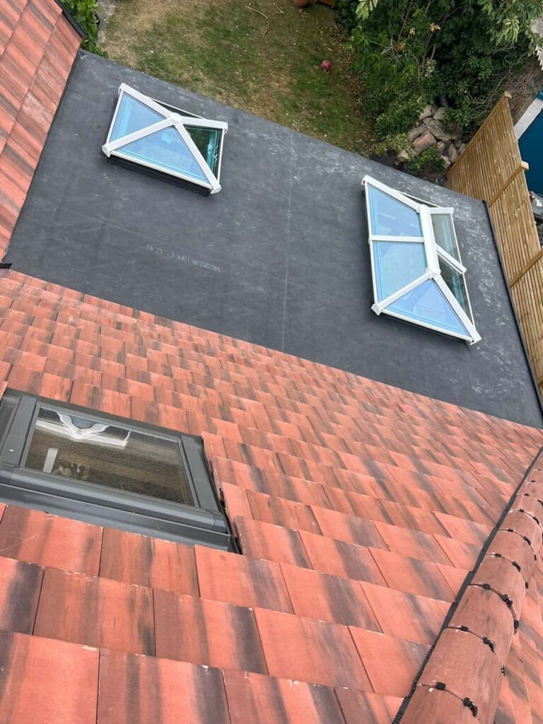 This is a photo taken from the roof ridge looking down a tiled pitched roof on to a flat roof. Works carried out by Kingswinford Roofing Repairs